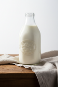 Half-gallon glass bottle of Two Ponds Provisions fresh local 2% milk on a rustic wooden surface