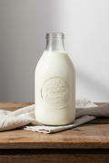 Half-gallon glass bottle of Two Ponds Provisions fresh local whole milk on a rustic wooden surface